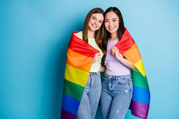 かわいいレズビアンカップルの女性の写真パレードショー寛容同じセックス結婚抱擁ホールドゲイの虹の旗を身に着けているカジュアルTシャツのジーンズ隔離された青の色の背景 — ストック写真