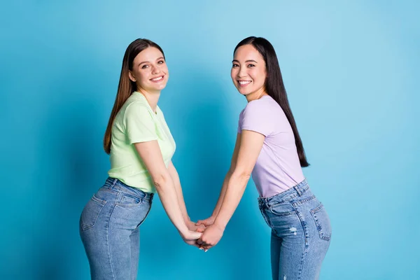 Profiel foto van twee aanhankelijke lesbiennes paar jonge studenten fellowship vrienden houden armen teder oprechte gevoelens dragen casual t-shirts jeans schoenen geïsoleerde blauwe kleur achtergrond — Stockfoto