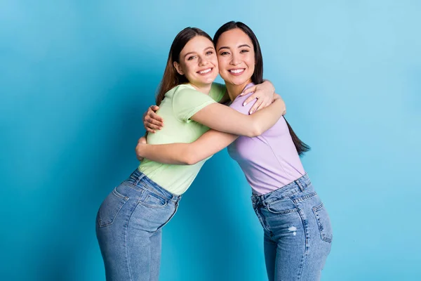 Profile photo of cheerful two people lesbians couple overjoyed hugging good mood young students best friends fellows buddies wear casual t-shirts jeans isolated blue color background — Stock Photo, Image