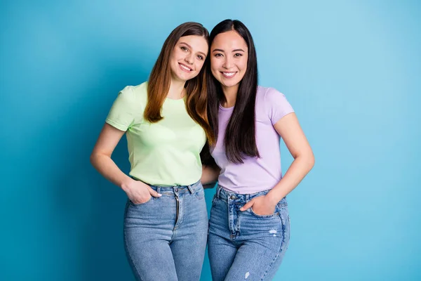 Foto av glada två personer damer lesbiska par överlycklig kramas gott humör unga studenter bästa vänner kompisar kompisar bär casual t-shirts jeans isolerad blå färg bakgrund — Stockfoto