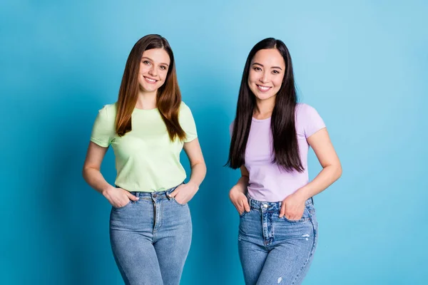 Foto de dos personas alegres damas lesbianas pareja alegre buen humor jóvenes estudiantes mejores amigos compañeros usan camisetas informales jeans aislados color azul fondo — Foto de Stock