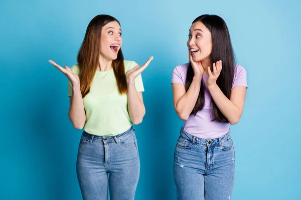 Photo de drôles fou deux personnes dames lesbiennes couple heureux réalisation pas croire yeux inattendu bonnes nouvelles porter casual t-shirts jeans isolé bleu couleur arrière-plan — Photo