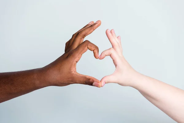 Närbild foto av två armar olika ras hudfärg multiracial par bästa vänner antirasism fråga koncept hjälp tillsammans visar hjärta figur kärlek spara världen isolerad grå bakgrund — Stockfoto