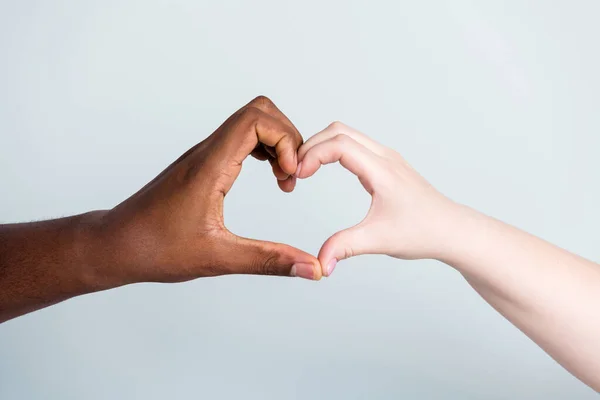 Closeup photo of two hands arms different race skin color multinational couple best friends anti racism issue help together showing heart figure love save world isolated grey background — Stock Photo, Image