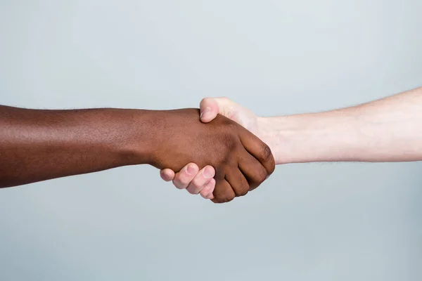 Крупным планом фото рукопожатия двумя руками различных расовых многонациональных друзей проблема антирасизма помочь вместе мировые партнеры по всему миру отношения иммиграции изолированы серый цвет фона — стоковое фото