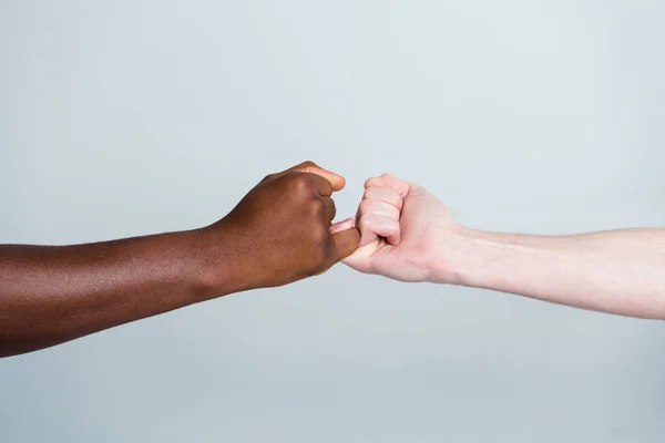 Primeros planos foto de dos manos brazos diferentes raza multinacional amigos antirracismo tema ayudar juntos la celebración de los dedos pequeños amigos juntos mundo globo socios aislados color gris fondo — Foto de Stock