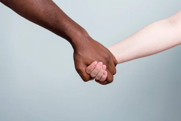 Primeros planos foto de dos manos brazos diferentes raza multinacional pareja mejores amigos anti racismo tema ayudar a mantener juntos el amor salvar mundo aislado gris color fondo — Foto de Stock