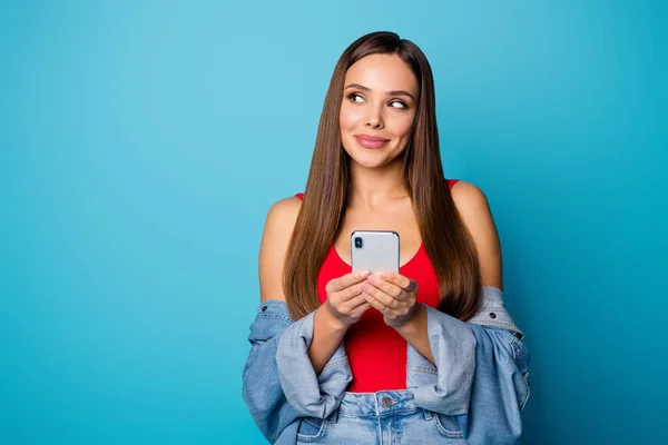 Portrait of positive cheerful addicted social network user girl use smartphone look copyspace have online communication with boyfriend wear red singlet tank-top isolated over blue color background — Stock Photo, Image