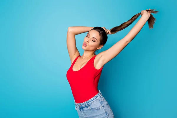 Portait de encantadora novia de ensueño prepararse para la fecha 14-febrero hacer coletas disfrutar de una nueva máscara de cuidado del cabello enviar aire beso desgaste denim rojo tanque-top aislado color azul fondo —  Fotos de Stock