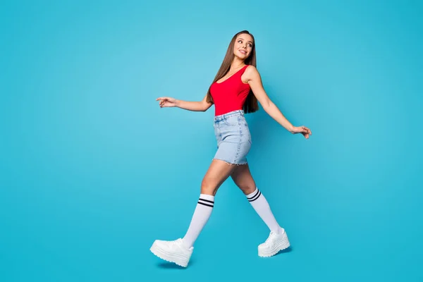 Full size profiel zijkant foto van schattige mooie inhoud meisje lopen gaan genieten lente vrije tijd weekend kijken copyspace slijtage benen schoenen tank-top geïsoleerd over blauwe kleur achtergrond — Stockfoto