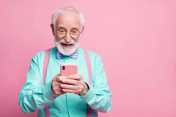 Portré a meglepett őrült megdöbbent öregember használata okostelefon olvasni a közösségi média hírek élvezze megjegyzések viselni rózsaszín ruhák lila ibolya csokornyakkendő elszigetelt pasztell rózsaszín háttér — Stock Fotó
