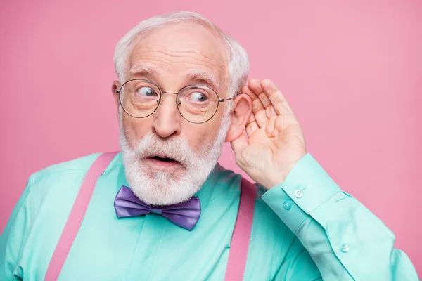 Närbild foto av attraktiv morfar hand nära örat lyssna rykten fokuserad pratkvarn dålig person bära specs mintskjorta hängslen violett rosett isolerad rosa pastell färg bakgrund — Stockfoto