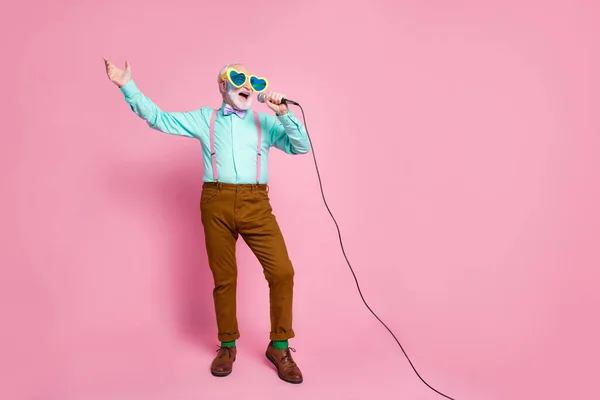 Full Size Foto von lustigen stilvollen Opa hält Karaoke-Mikrofon singen Party Songs Chillen tragen coole Spezifikationen Hemdträger Fliege Hose Socken isoliert rosa Pastellfarbe Hintergrund — Stockfoto