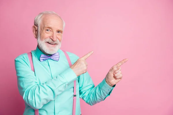 Bild av cool elegant utseende åldrad man kille som indikerar fingrar tomt utrymme erbjuder svart fredag låga priser bära mintskjorta hängslen violett rosett slips isolerad pastell rosa färg bakgrund — Stockfoto