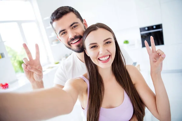 Retrato de positivo alegre casal homem mulher ficar quarentena casa fazer selfie show v-sign blogging in kitchen house indoors — Fotografia de Stock