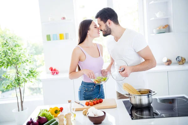 Photo de deux personnes passionnés tendres conjoints doux préparer valentin jour plat nutrition femme tenir bol salade homme faire bouillir macaroni baiser romance dans la cuisine maison à l'intérieur — Photo