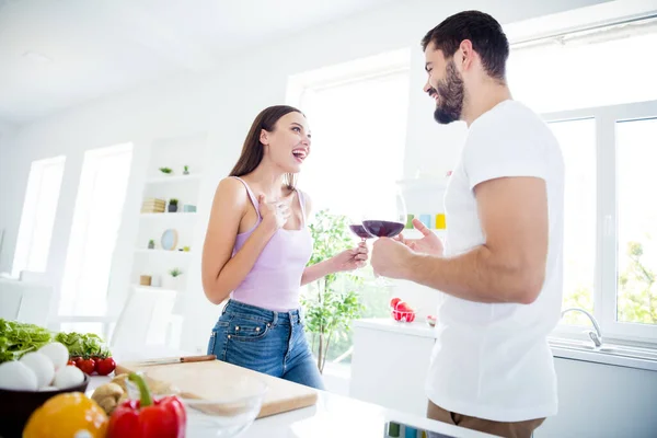 Foto av positiva två personer stannar hemma karantän har date man kvinna hålla glas vin säga berätta komisk humor nyheter njuta skratta i huset kök inomhus — Stockfoto