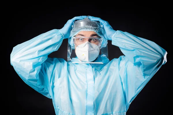 Foto de guy doc virologist eyes fear hold arms on head muchos enfermos covid patients wear respiratory hazmat blue uniform suit plastic facial protective shield isolated grey color background —  Fotos de Stock