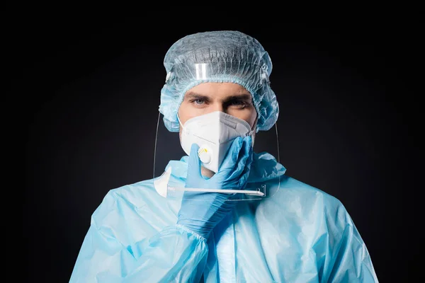 Primeros planos foto de chico experto doc cogida de la mano en el centro de virología barbilla covid19 protección desgaste máscara respiratoria hazmat azul uniforme traje plástico escudo facial aislado negro color fondo — Foto de Stock