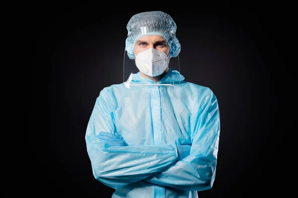 Photo of serious professional guy expert covid doc virology clinic arms cross wear face mask sterylny hazmat niebieski mundur garnitur plastik tarcza twarzy odizolowany czarny kolor tło — Zdjęcie stockowe