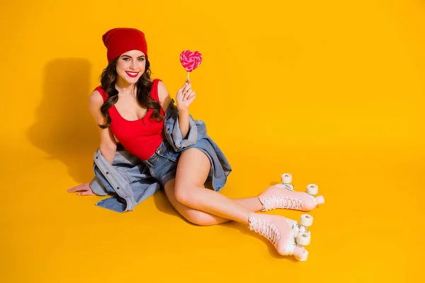 Top above high angle view full size photo positive trend student girl sit floor roller skate relax hold heart shape lolipop wear red singlet jeans headwear isolated bright color background