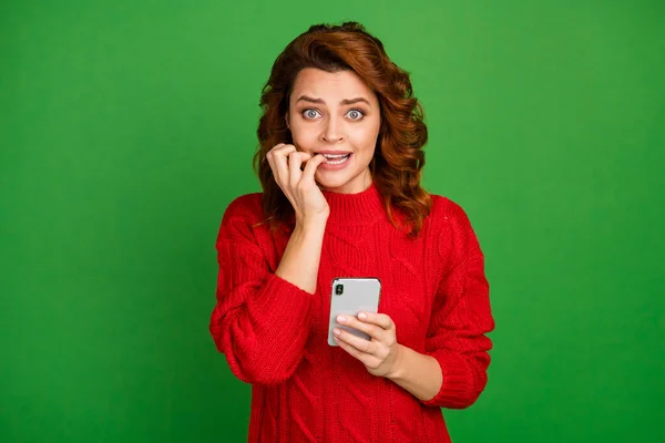 Portret van gefrustreerde angstige blogger vrouw gebruik smartphone nieuw sociaal netwerk post zorgen volgers abonnees feedback bijten nagels dragen gebreide trui geïsoleerde heldere glans kleur achtergrond — Stockfoto