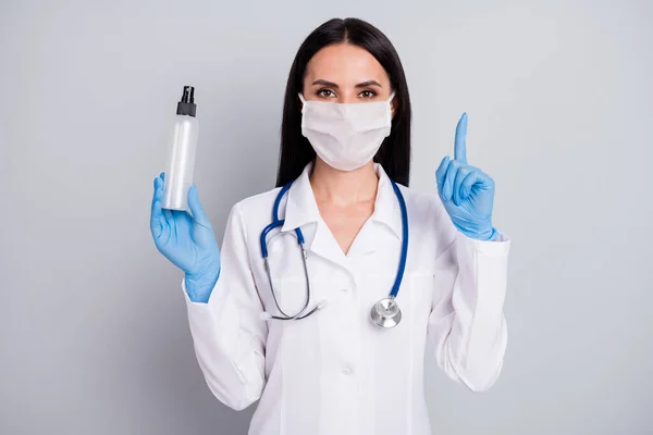 Retrato de cerca de ella ella agradable atractiva chica segura doctora terapeuta sosteniendo en botella de mano alcohol médico apuntando hacia arriba nueva solución aislada sobre fondo de color pastel gris — Foto de Stock