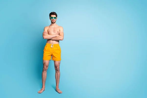 Взгляд в полный рост на его симпатичного привлекательного вирильного мужественного парня в купальных шортах скрестил руки на ярком ярко-синем бирюзовом фоне — стоковое фото