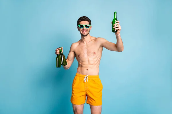 Neşeli, pozitif, çekici ve yakışıklı bir adamın elinde dört şişe bira olan fotoğrafı. Birini zevkten memnun bir şekilde yetiştirmek için izole edilmiş mavi pastel arka plan önerisi. — Stok fotoğraf