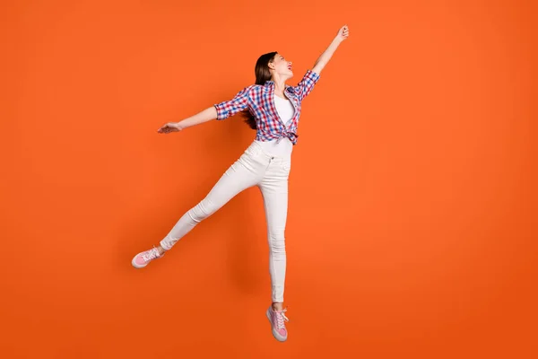 Pleine longueur profil photo latérale de fille gaie positive sauter tenir la main veulent attraper parasol sentir émotions drôles porter des vêtements de style décontracté isolé sur fond de couleur orange — Photo