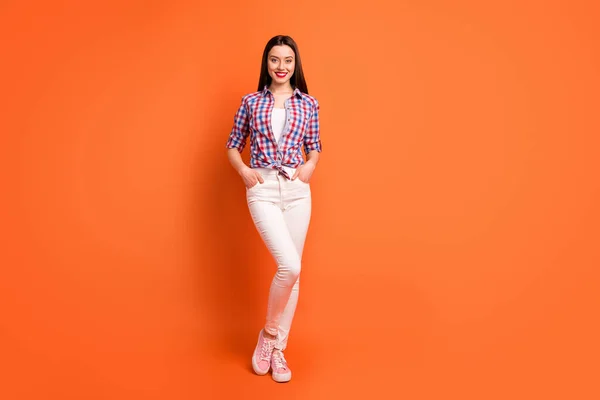 Полноразмерное фото очаровательной симпатичной девушки на летних каникулах надели белые брюки носить одежду хорошего вида, изолированную на оранжевом фоне — стоковое фото