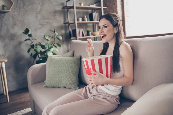 옆에 앉아 있는 쾌활 한 여자가 앉아 큰 상자를 들고 팝콘을 먹고 흥미 로운 영화 시리즈를 보면서 집에 있는 아파트에서 지내는 모습 — 스톡 사진