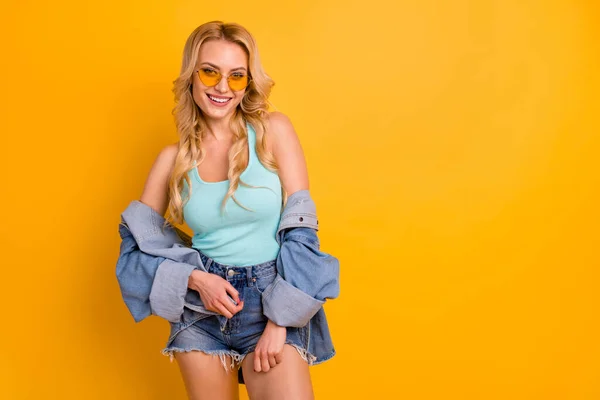 Photo of attractive lady long curly hairdo good mood summer sunny day weekend free time wear casual turquoise singlet denim mini shorts shirt sun specs isolated yellow color background — Stock Photo, Image