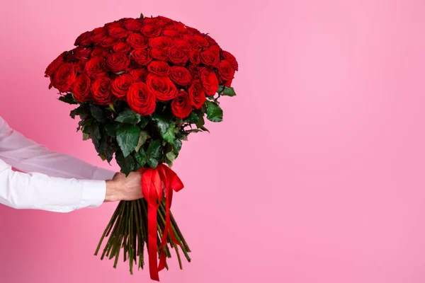 切り取られた男の腕の写真を保持大きな百個の赤い明るいバラの束を与えガールフレンド驚き隠された顔の秘密アドバイザー配置配信コンセプト隔離されましたピンク色の背景 — ストック写真
