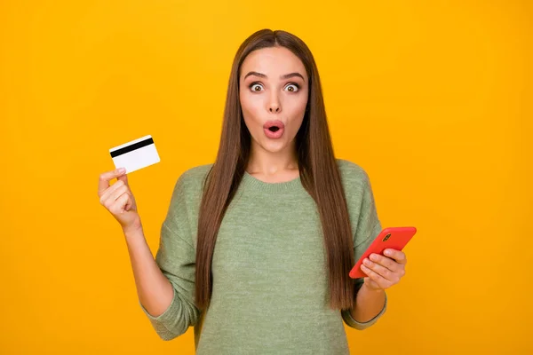 Porträtt av förvånad flicka använda smartphone imponerade kreditkort på nätet betalande bank system skrika wow omg otroligt slitage jumper isolerad ljus glans färg bakgrund — Stockfoto