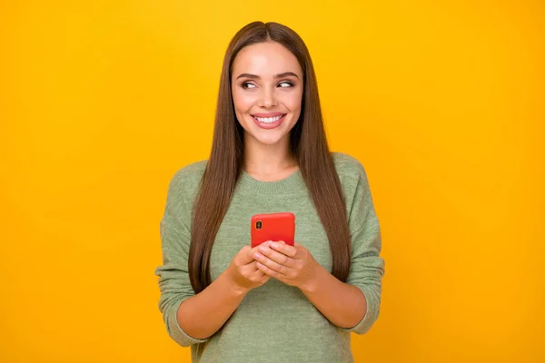 Portrait of positive cheerful inspired girl use cellphone look copyspace guess imagine what write on social media account wear pullover isolated over bright shine color background — Stock Photo, Image