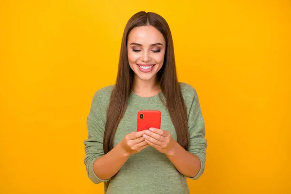 Ritratto di positivo allegro ragazza uso smartphone leggere social media notizie condividere ripubblicare iscriviti usura buon look pullover isolato su sfondo di colore brillante — Foto Stock