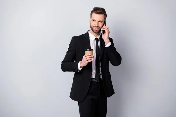 Portrait of positive agent man have work relax time hold take-out coffee beverage mug speak on cell phone colleagues family friends wear black pants blazer jacket isolated grey color background — Stock Photo, Image