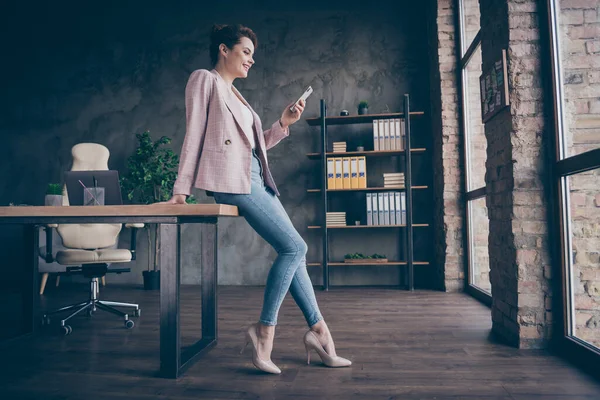 Full length body size profile side view of nice attractive cheerful focused businesslady using cell chatting online communication modern industrial loft brick style interior workplace workstation — Stock fotografie