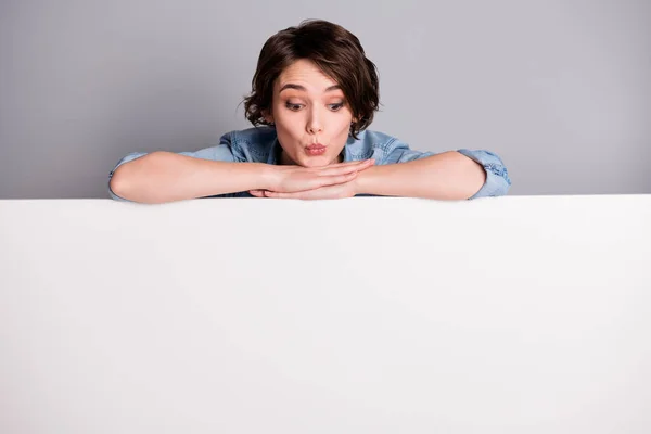 Foto de senhora alegre inclinando as mãos em grande cartaz de papel vazio propondo comprar anúncio local olhar para baixo interessado usar camisa jeans casual isolado fundo de cor cinza — Fotografia de Stock