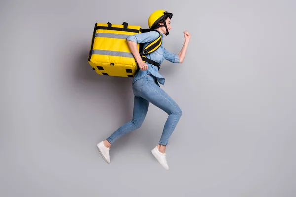 フル長さプロフィール側の写真の女の子宅配ジャンプ実行急いで配信食品家庭運ぶ黄色熱コンテナ着用デニムジーンズシャツの靴隔離されたグレーの色の背景 — ストック写真