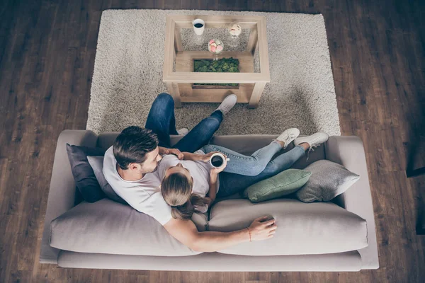 High angle above view photo of domestic pretty charming lady guy couple relaxing sit comfy couch staying home good mood quarantine hugging glad together living room indoors
