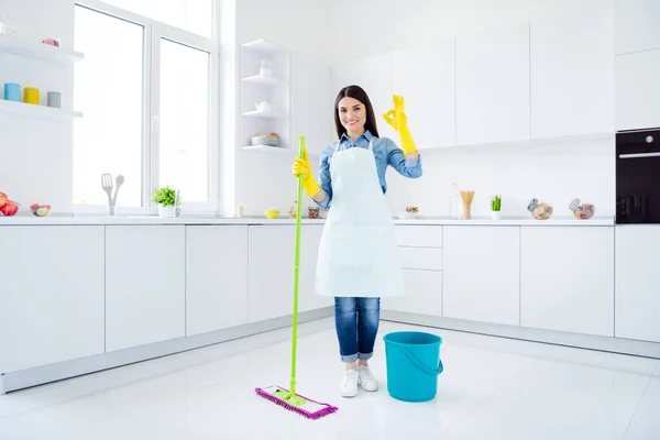 Full length body size view of her she nice attractive confident cheerful housemaid wiping neat tidy floor housekeeping showing ok-sign good job well done in modern light white interior kitchen house