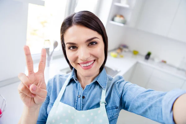 Zelfportret van haar ze mooi aantrekkelijk mooi leuk vrolijk vrolijke huisvrouw koken huishoudelijk restaurant huishouden tonen v-teken in modern licht wit interieur keuken huis — Stockfoto