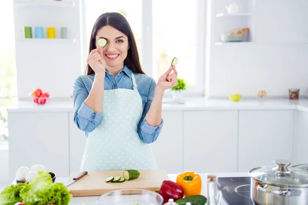 Ritratto di donna positiva premurosa casa moglie vuole preparare gustosa colazione cena per la sua famiglia tenere fetta di cetriolo chiudere gli occhi di copertura faccia in cucina al chiuso — Foto Stock