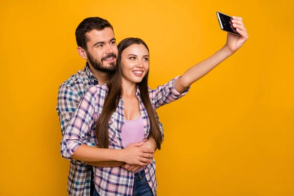 Sevecen, evli çiftlerin portresi yaz tatilinde randevulaşır. Selfie 'ye akıllı telefon kucaklaşması yaptırır. Kareli gömleği parlak renkli arka planda izole eder. — Stok fotoğraf