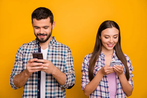 Foto atractiva dama guapo alegre chico pareja mirada teléfono pantalla adictos usuarios populares bloggers usar casual a cuadros camisas traje aislado color amarillo fondo —  Fotos de Stock