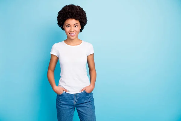 驚くほど美しい暗い肌の波状の女性の歯の笑顔良い気分陽気なライフポジションを身に着けているカジュアルな白いTシャツのジーンズ隔離された青の色の背景 — ストック写真