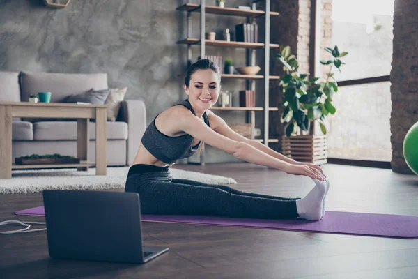 Full Size Profil Seite Foto von positiven aktiven sportlichen Energie Ausdauer Mädchen sitzen Fußmatte Uhr Laptop Pilates Workout Stretch Hüften Füße Beine im Haus drinnen — Stockfoto