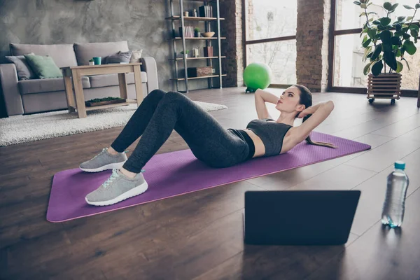 Foto in voller Größe von fokussierten aktiven sportlichen athletischen schönen Mädchen tun Video Online-Workout Laptop-Aerobic-Übung knirscht Pilates auf Bodenmatte im Haus drinnen — Stockfoto